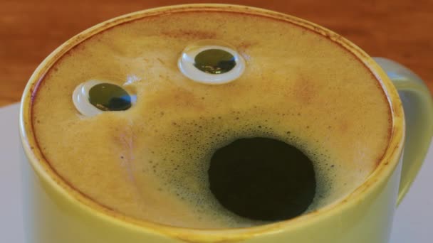 Smiling coffee man in a cup. Fragrant, lively coffee with eyes and mouth. Human face on fresh, milky coffee crema. High quality 4k footage - Video