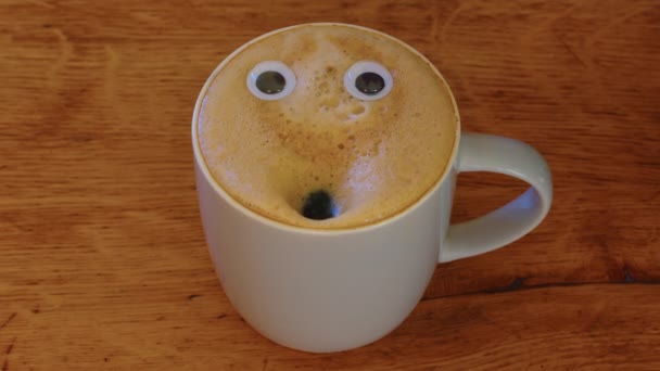 Close-up coffee cup with eyes and mouth screaming very loudly. Emoji coffee. Cheerful mood of the barista who made coffee with a human face. High quality 4k footage - Πλάνα, βίντεο