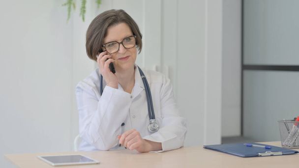 Senior Female Doctor Talking on Phone in Clinic - Foto, Imagen
