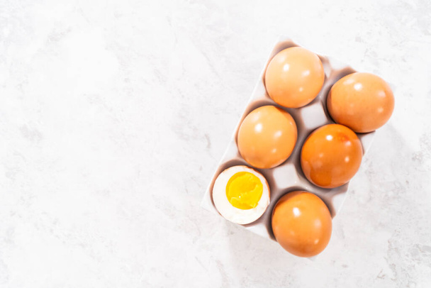 Hard-boiled eggs in a white ceramic egg crate. - Фото, изображение