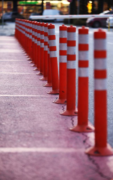 orange plastic cones with white stripes between the walking path and the car road - Φωτογραφία, εικόνα