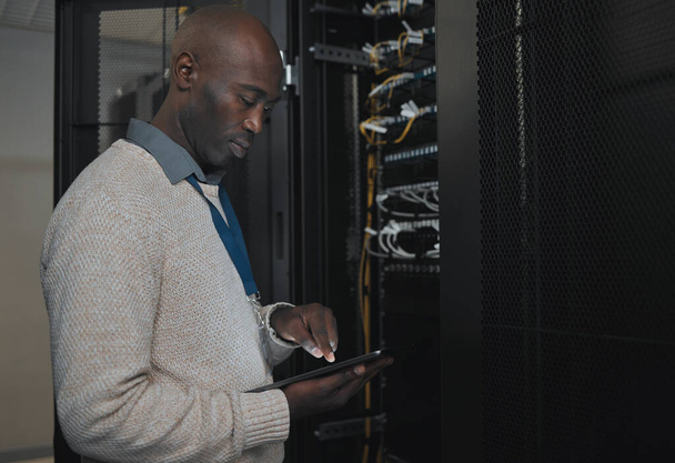 Engineer, server room or black man with tablet for database connection cable, maintenance or software update at night. Cybersecurity, IT and male coder with technology for networking in data center - Valokuva, kuva