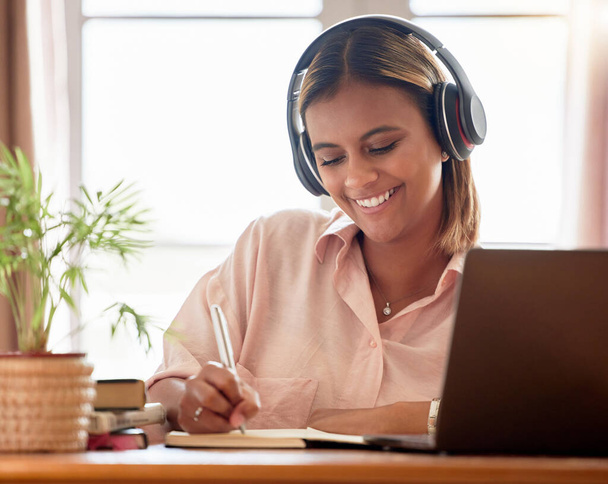 Woman, student with laptop and headphone, writing notes in notebook, education and study elearning course. Mexican female smile, internet and technology, online class with webinar and studying. - Fotoğraf, Görsel
