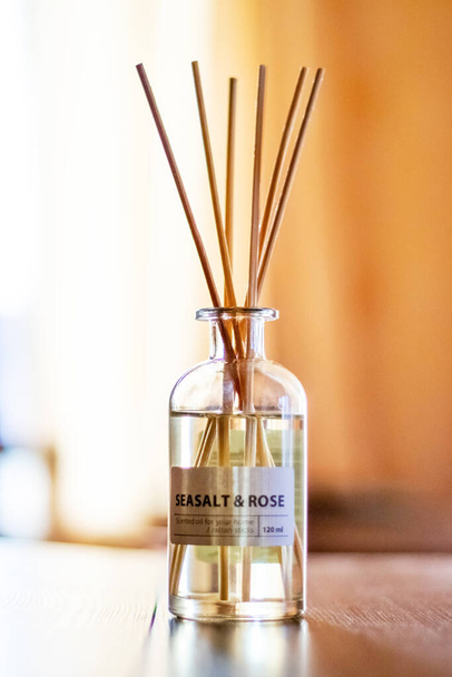 Un difusor de aroma con aceite aromático y palos en la habitación cerca de la ventana crea una atmósfera de paz y confort - Foto, Imagen