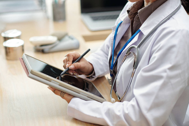 Врач заполнения медицинской карты пациента на планшетном компьютере - Фото, изображение