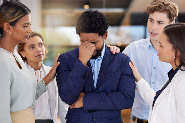 Black man, stress or headache with team for support on mental health and anxiety. Corporate leader with depression, burnout fatigue or tired and frustrated in office with empathy from men and women. - Foto, imagen