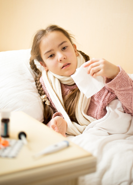 krankes Mädchen liegt im Bett und hält Papiertaschentücher - Foto, Bild