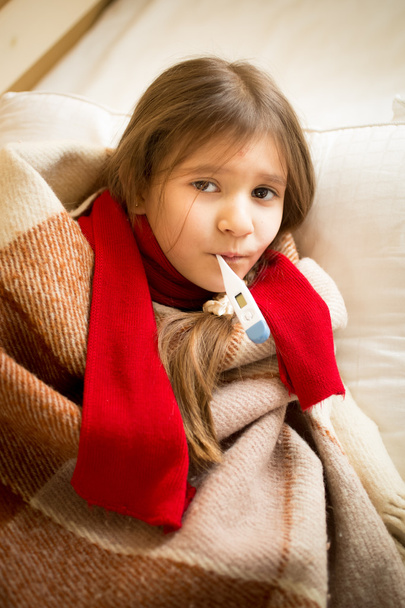niña acostada en la cama y sosteniendo el termómetro en la boca
 - Foto, Imagen