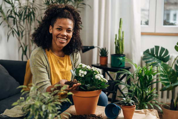 Heureuse femme métissée travaille avec des plantes avec un sourire sur son visage - Photo, image