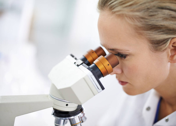 Aufnahme einer schönen Frau in einem Labor, die mit einem Mikroskop arbeitet. - Foto, Bild