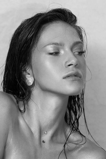 Close-up portrait of beautiful woman's purity face. Model with wet clean shiny skin. Small drops on the skin. Black and white photo. - Valokuva, kuva
