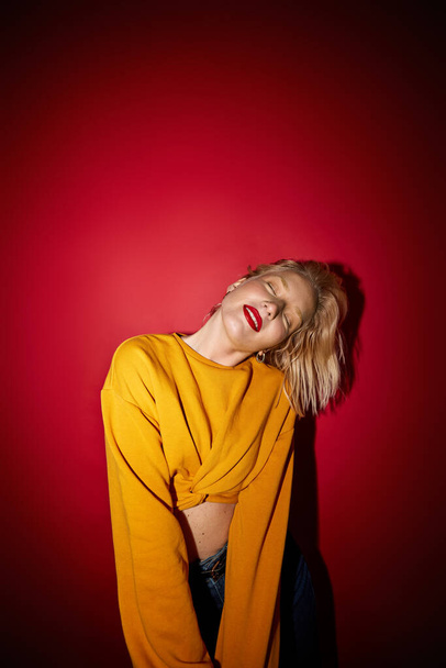 Beauty portrait of a pretty blonde with natural pure skin isolated on red background. - 写真・画像
