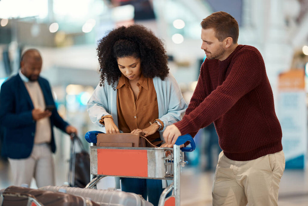 Travel, airport and interracial couple search for ticket. boarding passport and ID documents in luggage. Plane transport, dating and man and black woman check in suitcase, trolley and wait for flight. - Valokuva, kuva