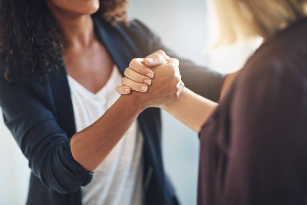 Cropped shot of two businesswomen shaking hands in solidarity at work. - 写真・画像