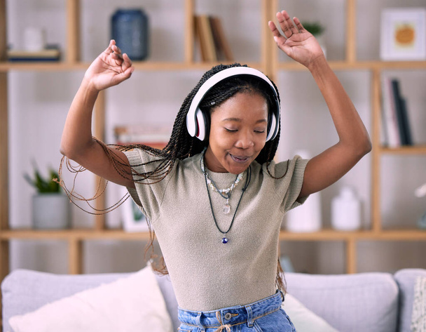 Mujer negra, bailes y auriculares musicales en casa sala de estar con energía y conexión wifi. Jóvenes bailan mientras escuchan audio, sonido y radio o podcast para libertad, motivación y relax. - Foto, Imagen