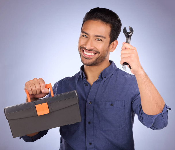 Portrét, nástroj a asijský muž s krabicí, úsměv a údržba s chlapem na modrém pozadí studia. Tvář, mužský zaměstnanec a údržbář se štěstím, vybavením a dodavatelem. - Fotografie, Obrázek