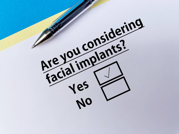 A person is answering question about cosmetic surgery. She is considering facial implants. - Φωτογραφία, εικόνα