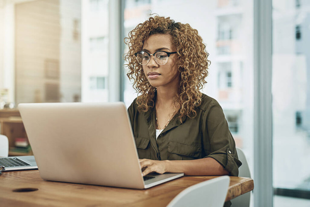 Aufnahme einer jungen Geschäftsfrau mit einem Laptop an ihrem Schreibtisch in einem modernen Büro. - Foto, Bild