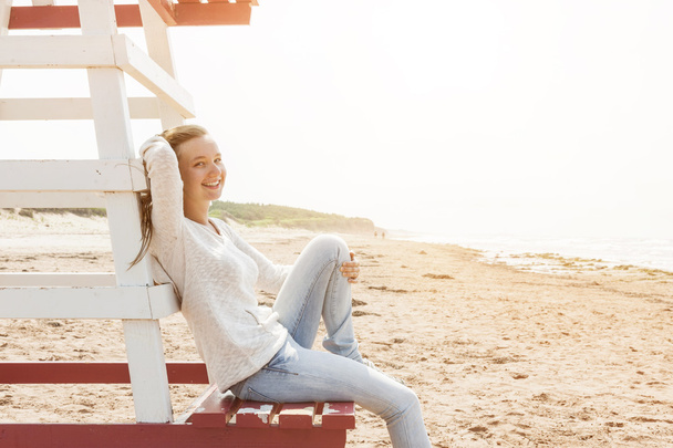 Young woman sitting on beach lifeguard chair - Foto, imagen