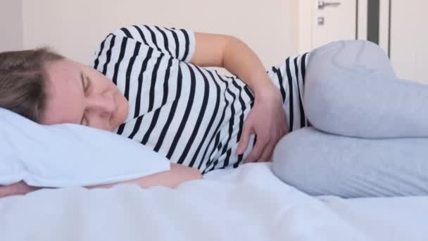 Suffering sick woman lies on the bed and holds her stomach. Stomach ache. Menstrual pain - Video