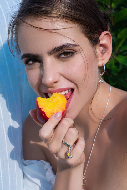 Young sexy lady at the village. Woman eat peach, close up. Country girl with peach close up. Close up woman face eating peach in nature - Foto, Imagen