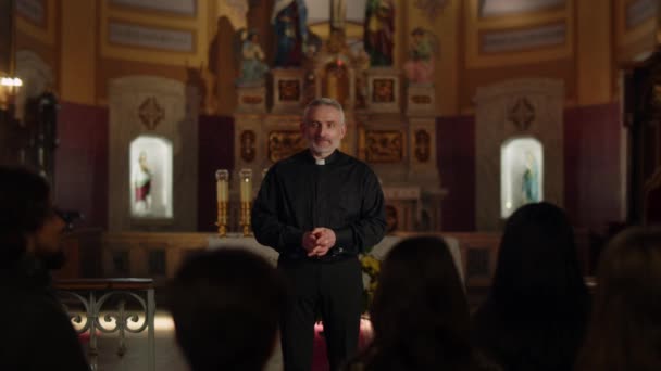 A gray-haired Catholic priest conducts a Sunday service. The priest throws up his hands and looks up while praying. High quality 4k footage - Filmmaterial, Video