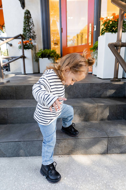 baby girl in long sleeve shirt and blue jeans standing on porch stairs near house in Miami  - Fotografie, Obrázek