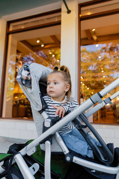 幼児子供で縞模様の長袖シャツに座っている赤ちゃんベビーカー近くショーケースの店でマイアミ  - 写真・画像