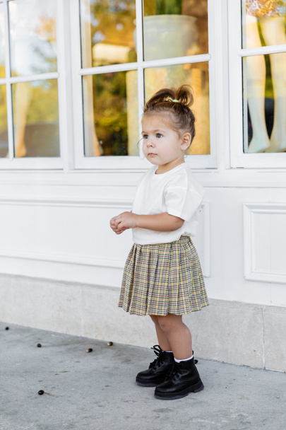 full length of toddler girl in skirt and white t-shirt standing near house  - Fotó, kép