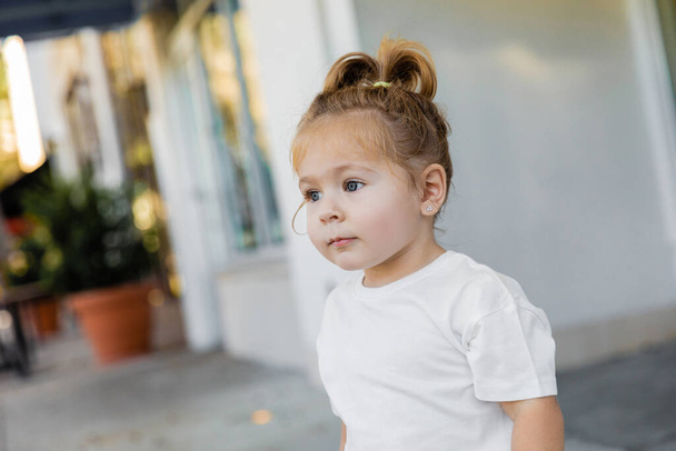 Porträt eines kleinen Mädchens mit grauen Augen, das auf der Straße in Miami wegschaut  - Foto, Bild