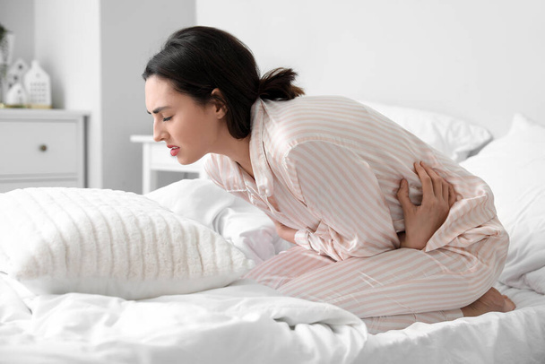 Young woman having menstrual cramps in bedroom - Foto, Imagem
