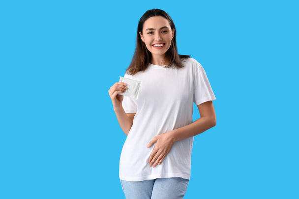 Young woman with menstrual pad on blue background - Zdjęcie, obraz
