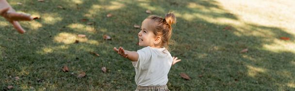 niña feliz niño de pie con las manos extendidas mientras juega en el parque, pancarta  - Foto, imagen
