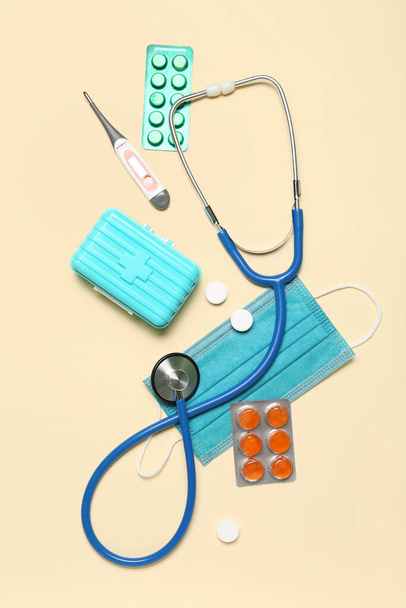 Stethoscope, thermometer, pills and medical mask on beige background. World Health Day - Valokuva, kuva