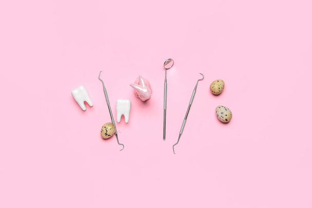 Dental tools with plastic teeth, Easter rabbit and eggs on pink background - Photo, Image
