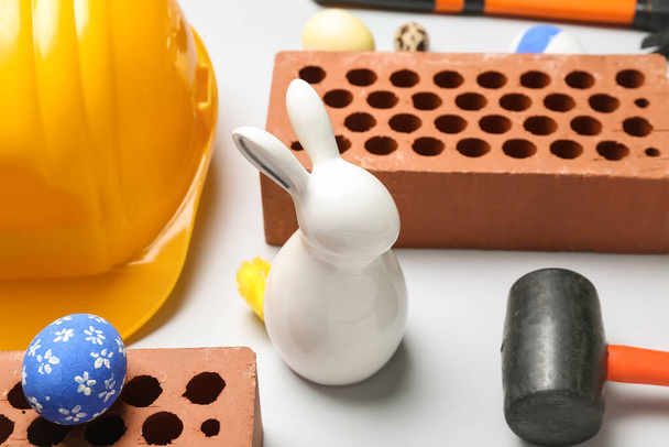 Easter rabbit with eggs and builder's tools on white background, closeup - Fotoğraf, Görsel