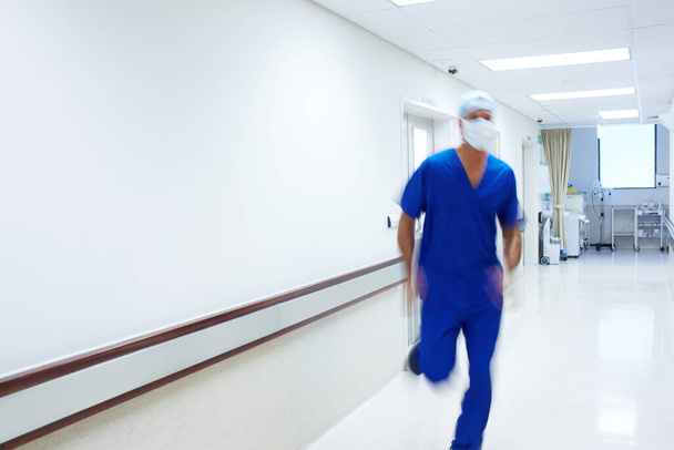 His patients rely on his quick actions. A doctor rushing in the passage of a hospital - 写真・画像