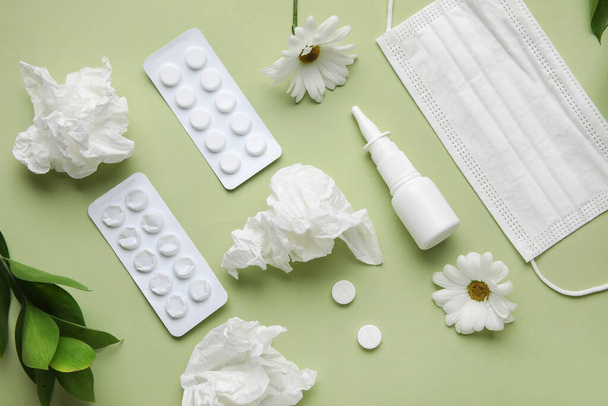 Nasentropfen mit Pillen, Blumen, medizinischer Maske und Gewebe auf grünem Hintergrund. Saisonales Allergiekonzept - Foto, Bild