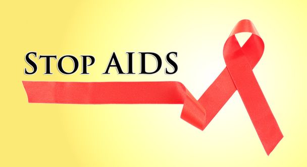 Red AIDS ribbon on yellow background - Foto, Imagen