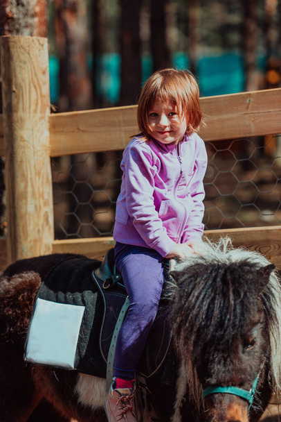 Little happy girl having fun in the park while riding small horses. - Valokuva, kuva