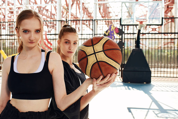 Lányok a főtéren fognak kosarazni, nézik a kamera streetball, életmód, aktív életmód - Fotó, kép