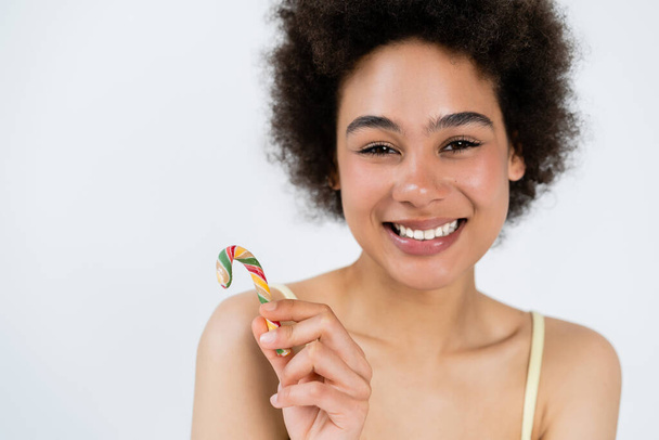 Χαρούμενη Αφρο-Αμερικανίδα που κρατάει το ζαχαροκάλαμο απομονωμένο στο γκρι.  - Φωτογραφία, εικόνα