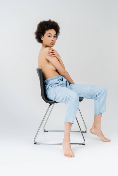 Shirtless african american woman posing on chair on grey background  - Foto, immagini