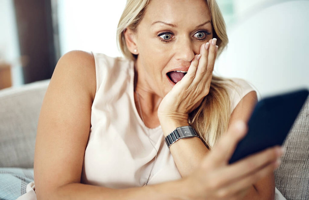Whaaat. an attractive mature woman looking surprised while reading a text message at home - Фото, изображение