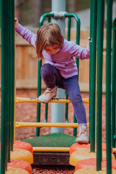 A little girl playing in the park. The concept of family socializing in the park. A girl swings on a swing, plays creative games.  - Foto, Imagen