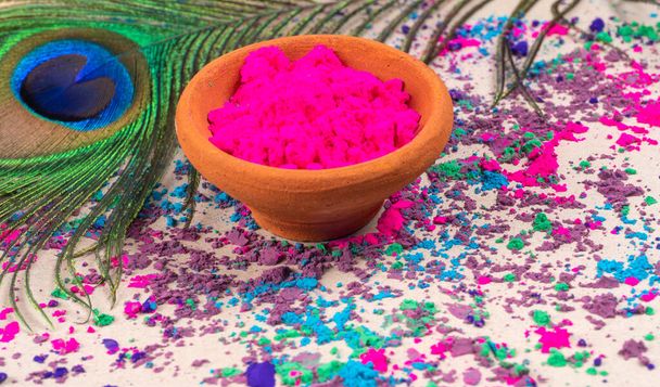 Růžový prášek pro holi na hliněném hrnci u příležitosti indického festivalu barev. šťastný holi téma záběr s páví peří. - Fotografie, Obrázek