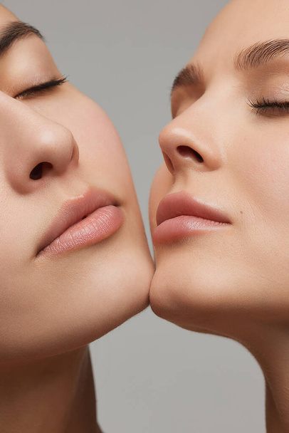 Lips. Vertical cropped portrait of young beautiful female couple. Models with well-kept skin and nude makeup. Concept of emotions, beauty, vision, health and fashion. - Photo, Image