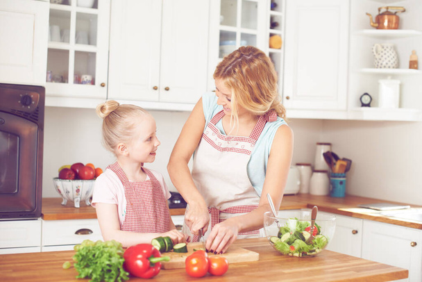 Ensinando-a a fazer uma salada. Jovem mãe e sua filha fazendo uma salada juntos - Foto, Imagem