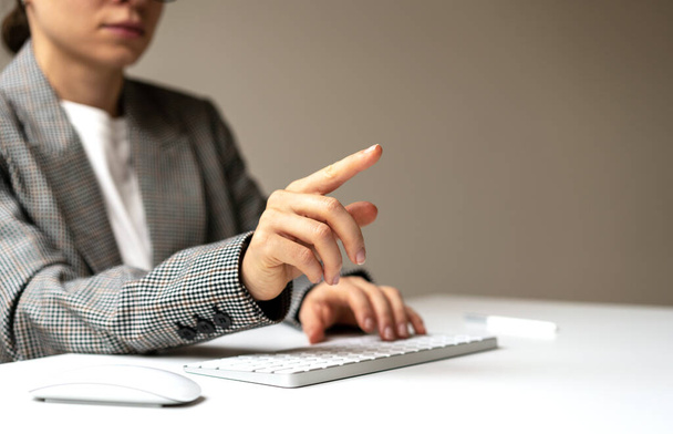 Femme assise au bureau travaillant sur un ordinateur touchant un écran virtuel avec un doigt. - Photo, image