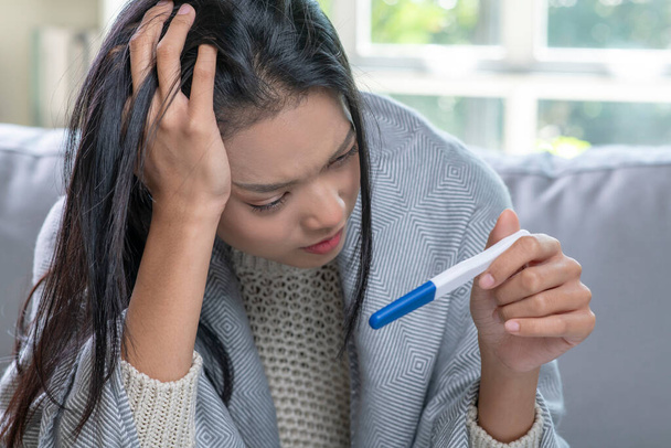 Deprimida jovem asiática segurando teste de gravidez negativo ou positivo. - Foto, Imagem